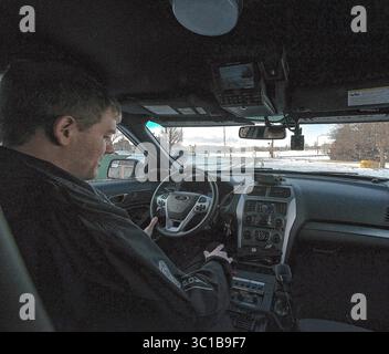 20 febbraio 2015 - Emporia, Kansas, Stati Uniti - Emporia, Kansas USA 17 febbraio 2015.4:48 PM ufficiale Schuman all'interno del nuovo incrociatore della polizia. Dotato di radar di velocità, 3 diversi sistemi radio per comunicare con i dispatcher della polizia di campus, città e contea. È inoltre dotata di una telecamera di retromarcia per quando il conducente esegue la retromarcia del veicolo in modo che possa vedere dietro di sé. Dispone inoltre di molte luci e sirene e di un fucile montato in un rack tra i sedili anteriori. E una telecamera montata che punta verso l'auto anteriore attraverso il parabrezza per registrare le fermate che l'agente fa. (CR Foto Stock