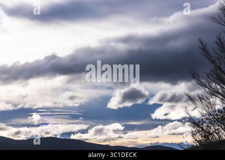la luce del sole si irrompe attraverso nuvole bianche e scure sulle montagne della tasmania, piena di contrasto, umore e bellezza naturale Foto Stock