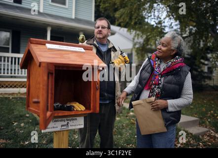 22 ottobre 2013 - Minneapolis, Minnesota, USA - Stati Uniti - Little Free Libraries creatore Todd Bol e Eddye Watkins, a destra, il cui cortile è stata eretta la biblioteca, collocare pezzi decorativi in cima alla Amish Made, biblioteca in legno martedì 22 ottobre 2013, a Minneapolis, MN. Le prime piccole biblioteche libere sono state collocate un paio di anni fa a Hudson, Wisconsin. Ora CE ne sono più di 10.000 in tutto il mondo e il fenomeno non mostra segni di arresto. Todd Bol, che ebbe l'idea di Little Free Libraries, installò una di queste biblioteche di dimensioni ridotte nel cortile di Eddye Watkin. L'idea è Foto Stock