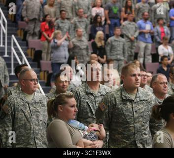 13 giugno 2015 - St. Paul and Anoka, MN, Stati Uniti - cerimonia ufficiale di ritorno della 34th Combat Aviation Brigade's Headquarters Company e 2nd Battalion, 147th Assault Helicopter Battalion da un dispiegamento di un anno a sostegno dell'operazione Enduring Freedom-Kuwait e dell'operazione Inherent Resolve in Iraq sabato 13 giugno, presso l'Anoka College di Anoka, Minnesota. Il gruppo tornò a casa nel maggio del 2015. Kyle Myers, davanti a destra, sta per l'inno nazionale con sua moglie Caitlin e la figlia Charlotte, sei mesi. La cerimonia ufficiale di ritorno della 34th Combat Aviation Brigade Headquart Foto Stock