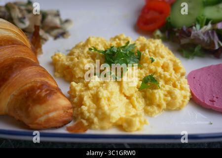 Piatto della colazione con uova strapazzate e croissant in un caffè Foto Stock
