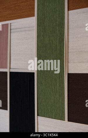 Motivo geometrico a blocchi di colore realizzato in filato o filo avvolto. Sfondo astratto con arte tessile nei colori verde, rosa, marrone e nero. Foto Stock