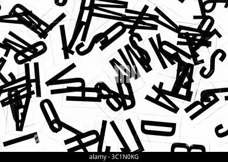 Layout con lettere nere sparse irregolarmente su sfondo bianco. Lettere nere disposte con cautela su sfondo bianco retroilluminato. Foto Stock