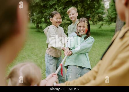 Gruppo di bambini diversi che giocano a Tug of War nel parco Foto Stock