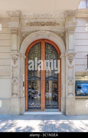 Porta d'ingresso ornata di un edificio storico di Barcellona. Porta ad arco in legno, griglia in ferro battuto. Architettura classica spagnola, facciata urbana europea, D. Foto Stock