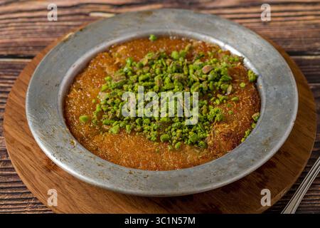 Kunefe tradizionale con pistacchi su un tavolo di legno Foto Stock