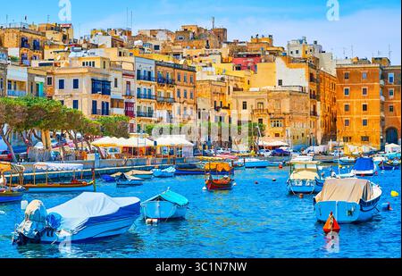 Osserva i quartieri residenziali di L-Isla dal mare, con una vista sulle barche del porto turistico di Vittoriosa in primo piano, Senglea, Malta Foto Stock