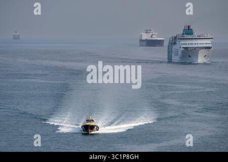 Pilota di porto che naviga di fronte alle navi che accedono al porto di Barcellona, Catalogna, Spagna. Foto Stock