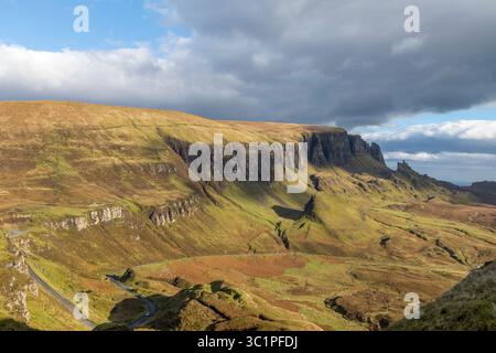 Il Quiraing sull'isola di Skye sotto cieli spettacolari, con aspre colline verdi, strade tortuose e laghi lontani che creano un iconico paesaggio delle Highland Foto Stock