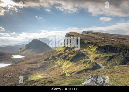 Il Quiraing sull'isola di Skye sotto cieli spettacolari, con aspre colline verdi, strade tortuose e laghi lontani che creano un iconico paesaggio delle Highland Foto Stock