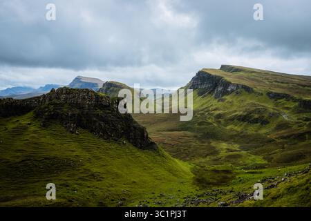 Il Quiraing sull'isola di Skye sotto cieli spettacolari, con aspre colline verdi, strade tortuose e laghi lontani che creano un iconico paesaggio delle Highland. Foto Stock