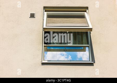 Finestra di vetro aperta con tenda e riflesso del cielo sulle pareti beige della villa sotto la luce del sole. Svezia. Foto Stock