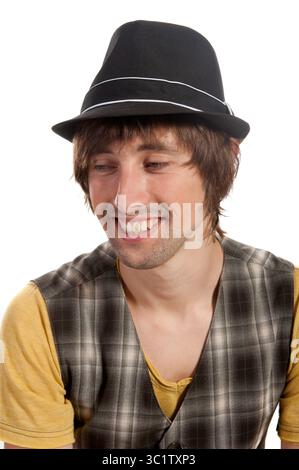 Un giovane uomo travi di gioia, vestito con un gilet a motivi geometrici e un cappello elegante. Foto Stock