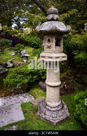 Tradizionale lanterna in pietra situata in un lussureggiante giardino giapponese Foto Stock