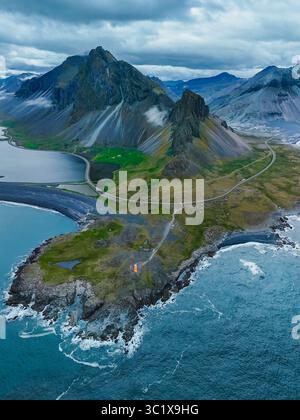 Ampie vedute mostrano la splendida costa delle ghiacciaie, evidenziando aspre montagne con vegetazione lussureggiante. L'interazione tra terra e mare è mozzafiato, la riserva naturale di Hvalnes in Islanda Foto Stock