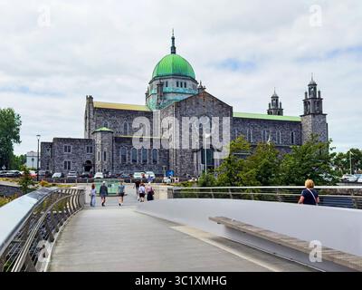 Una vista della cattedrale di Galway dal nuovo ponte pedonale chiamato Droichead an Dochais in irlandese, il Ponte della speranza, sul fiume Corrib Foto Stock