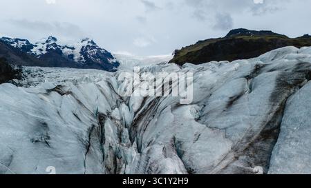 Esplora il paesaggio mozzafiato del ghiacciaio Svinafellsjokull in Islanda, caratterizzato da incredibili crepacci ghiacciati e montagne spettacolari. Foto Stock