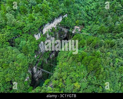 Guizhou. 22 luglio 2025. Una foto aerea scattata il 22 luglio 2025 mostra una vista panoramica di una dolina gigante nella contea di Kaiyang, nella provincia di Guizhou, nella Cina sud-occidentale. La provincia di Guizhou è rinomata per il suo vasto paesaggio carsico, che si distingue per le sue numerose doline giganti, chiamate localmente "tiankeng" o "pozze paradisiache". Le doline naturali sono sempre più riconosciute per i loro valori turistici unici. Crediti: Ou Dongqu/Xinhua/Alamy Live News Foto Stock