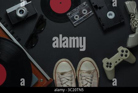Intrattenimento e supporti retrò piatti. Lettore di dischi in vinile con registrazione in vinile, telecamera, videocassetta, audiocassetta, gamepad, ricevitore su un blac Foto Stock