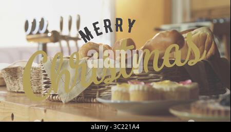 Con cesto di vimini che contiene croissant e panini in cucina, con cupcake e saluto natalizio Foto Stock