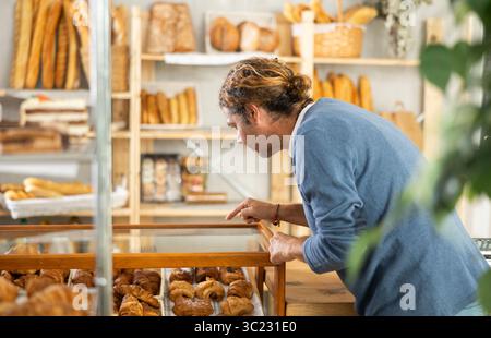 Cliente di mezza età che sceglie croissant in panetteria Foto Stock
