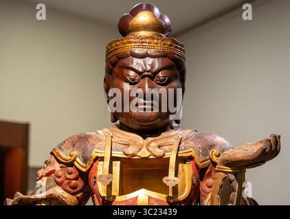 Primo piano sulla faccia arrabbiata del Buddha scolpita in legno Foto Stock
