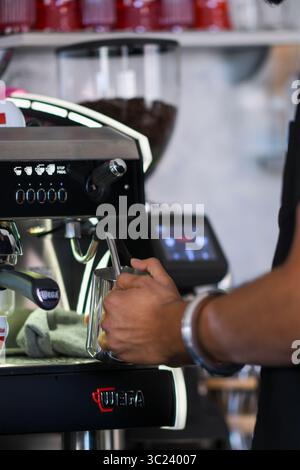 Cremona, Italia - 19 luglio 2025 Barista esperto cuoce sapientemente il latte creando consistenze schiumose per deliziose preparazioni di bevande calde in un caffè moderno Foto Stock
