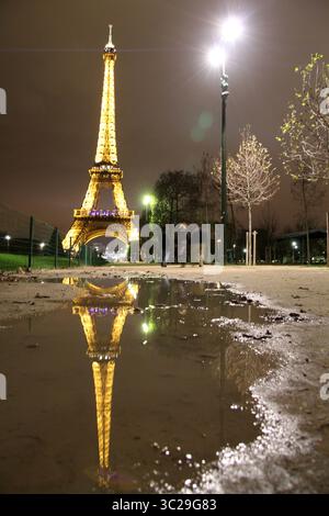 torre eiffel notturna riflessa in una pozzanghera Foto Stock