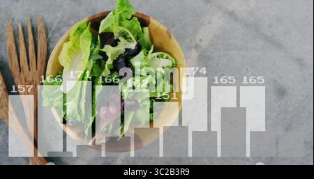 Mostra una ciotola di legno di insalata verde-viola seduta sul bancone con una tabella degli utensili con i numeri Foto Stock