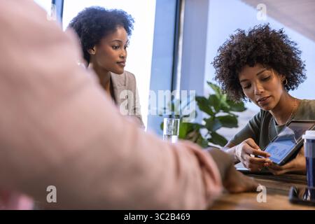 Colleghi diversi che discutono i dati grafici sul tablet al tavolo delle riunioni in legno in ufficio, spazio di copia Foto Stock