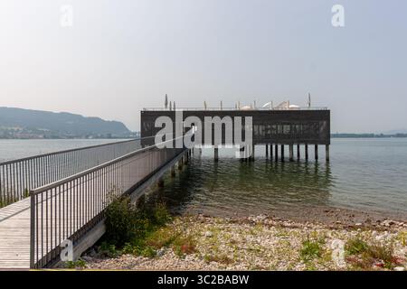Un lungo e moderno molo in legno con eleganti ringhiere in metallo si estende sulle calme acque del lago di Costanza (Bodensee) a Lochau, Austria Foto Stock