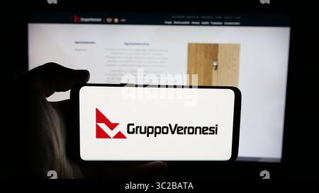 Stoccarda, Germania - 05-31-2025: Persona che detiene il cellulare con il logo dell'azienda alimentare italiana Veronesi Holding S.p.A. sullo schermo di fronte alla pagina web. Foto Stock