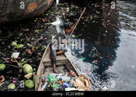 7 aprile 2019 - Dacca, Bangladesh - Un ragazzo raccoglie una bottiglia di plastica dal fiume inquinato Buriganga a Dacca in Bangladesh. Il fiume Buriganga, che scorre oltre la città di Dacca, è attualmente uno dei fiumi più inquinati del Bangladesh. La città di Dacca scarica circa 4.500 tonnellate di rifiuti solidi ogni giorno e la maggior parte di essi viene rilasciata nel Buriganga. L'acqua di questo fiume è ormai così inquinata che tutti i pesci sono morti, e l'aumento della sporcizia e dei rifiuti umani l'hanno trasformata in un gel nero. Anche remare lungo il fiume è ora difficile perché puzza così male. (Immagine di credito: © Kazi Salahuddin/ZUMA Wire/ZUMAPR Foto Stock