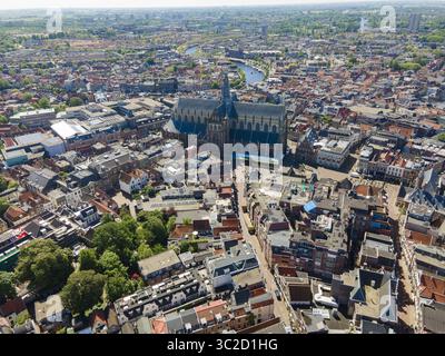Vista aerea della maestosa chiesa di San Bavone che sorge sopra le labirintiche strade, incorniciata da canali e tetti sotto un cielo luminoso, Haarlem, Olanda settentrionale, Paesi Bassi. Foto Stock