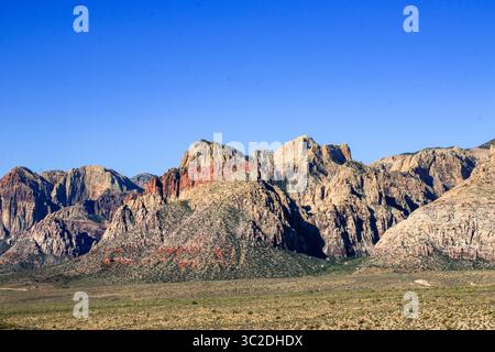 Ampio paesaggio desertico caratterizzato da imponenti montagne di roccia rossa dai colori vivaci. Foto Stock