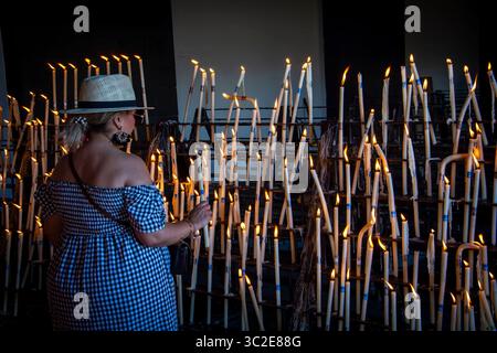Almonte, Huelva, Spagna. 5 giugno 2025. Una signora anziana con un cappello che accende una candela nel santuario della Virgen del Rocio ad Almonte, in Spagna. Foto Stock