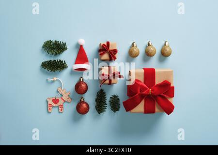 Composizione abbinabile di decorazioni natalizie con omaggi in miniatura, baubles, rami dell'albero di Natale, baubles, cappello di babbo natale su sfondo azzurro Foto Stock
