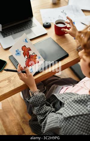 La freelance ama il lavoro estivo dal suo appartamento, dipingendo mentre sorseggia un caffè. Foto Stock