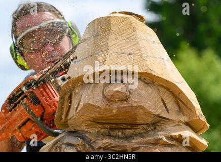 24 luglio 2025, Repubblica Ceca, Bo·í Dar: Chainsaw carver Raik Zenger di Bad Düben del team di scultura Bozi Dar sta lavorando alla mascotte di Oberwiesenthal Fichtelchen. Nell'ambito del progetto interculturale "The Christ Child and Fichtelchen for Children Without Borders", cinque artisti di motoseghe stanno attualmente lavorando a nuove sculture in legno per i sentieri escursionistici transfrontalieri tra Oberwiesenthal e Bozi Dar nella Repubblica Ceca. Il Woodcarving Pleinair ceco-sassone durerà quest'anno fino al 26.07.2025. Foto: Hendrik Schmidt/dpa Foto Stock