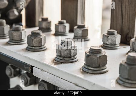 Primo piano di dadi e bulloni galvanizzati che fissano la flangia in acciaio in un moderno telaio architettonico Foto Stock