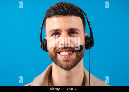 Un addetto all'assistenza clienti sorridente che indossa l'auricolare in primo piano su sfondo blu Foto Stock