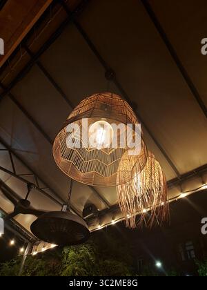 Le luci a sospensione intrecciate sono appese al soffitto e diffondono una luce calda in un ambiente interno accogliente, migliorando l'atmosfera invitante Foto Stock
