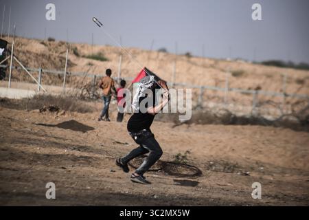 Luglio 12, 2019 - Gaza, Khan Younis, Palestina - un dimostrante palestinese utilizza un slingshot per scagliare pietre contro le forze israeliane durante scontri pur dimostrando chiedendo la fine al blocco israeliano della Striscia di Gaza e rivendicano il diritto di tornare alle loro case durante la recinzione di confine tra Israele e la striscia di Gaza nel sud della striscia di Gaza. (Credito Immagine: © Yousef Masoud/SOPA immagini via ZUMA filo) Foto Stock