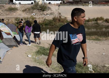 I migranti camminano vicino a un campo improvvisato vicino al confine di Ciudad Juarez, evidenziando le sfide umanitarie in corso affrontate da coloro che chiedono asilo negli Stati Uniti Foto Stock