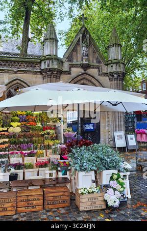 Flower stand di fronte a una chiesa gotica in Kensington High Street a Londra Foto Stock