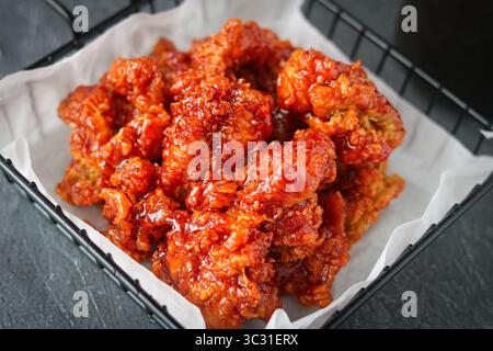 Primo piano di Yangnyeom Chicken, un popolare pollo fritto coreano ricoperto da una salsa rossa appiccicosa, dolce e piccante. Foto Stock