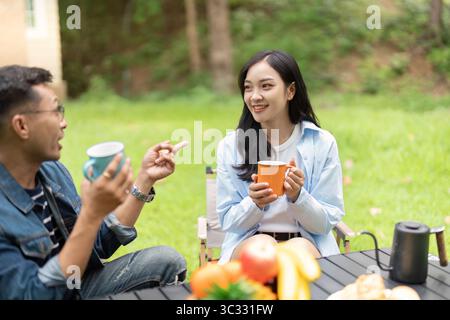 Conversazione coinvolgente. Giovane coppia che condivide caffè e risate all'aperto. Foto Stock