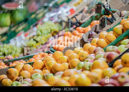 Vista grandangolare di una varietà di frutta fresca, principalmente arance, mele e uva, esposta in casse di plastica verdi in un mercato di strada durante la notte. Foto Stock
