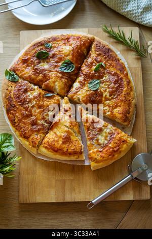Vista dall'alto, pasta madre, pizza al formaggio fatta in casa con foglie di basilico Foto Stock