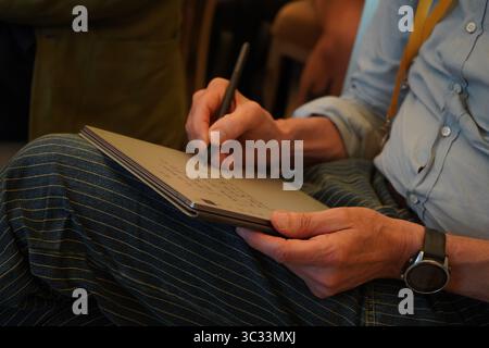 Una persona prende appunti scritti a mano su un tablet durante una conferenza. Primo piano di mani, penna digitale e notebook. Foto Stock